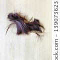 Strands of dark purple hair on light wood background 139073623