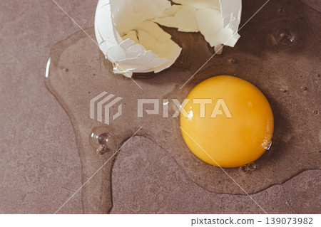 Egg yolk and white spilled on a dark countertop, symbolizing healthy food and essential minerals for cooking. Egg yolk and white spilled on a dark countertop, symbolizing healthy food and essential minerals for cooking. 139073982