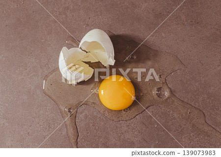 Cracked egg yolk and albumen spilling on a dark counter, symbolizing fresh nutrition, protein source and healthy diet Cracked egg yolk and albumen spilling on a dark counter, symbolizing fresh nutrition, protein source and healthy diet 139073983