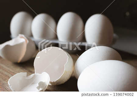 White eggs with cracked shells on a rustic wooden surface, evoking fresh, farm-style nutrition and protein-rich cooking White eggs with cracked shells on a rustic wooden surface, evoking fresh, farm-style nutrition and protein-rich cooking 139074002