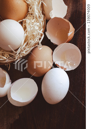 A top view of eggs in a basket and some eggshells on a wooden board, highlighting the essential vitamins and organic benefits. A top view of eggs in a basket and some eggshells on a wooden board, highlighting the essential vitamins and organic benefits. 139074009