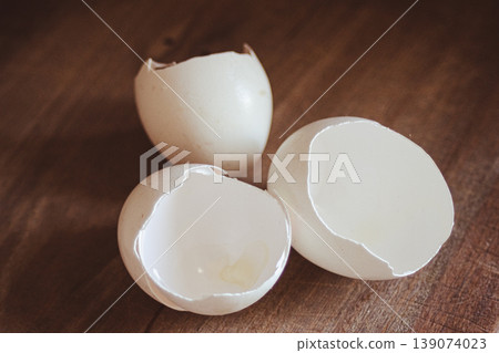 Cracked white eggshells on a wooden surface, showing the empty interior.Healthy cooking and sustainable kitchen waste concept 139074023