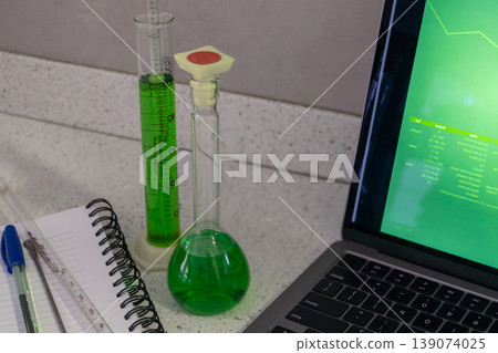 Horizontal image of laboratory glassware next to a laptop screen displaying graphs and data tables representing scientific or medical research. Horizontal image of laboratory glassware next to a laptop screen displaying graphs and data tables representing scientific or medical research. 139074025