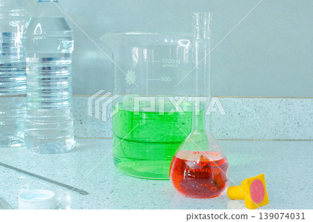 Laboratory counter with beakers, flasks and clear bottles symbolizing research, learning and discovery Laboratory counter with beakers, flasks and clear bottles symbolizing research, learning and discovery 139074031