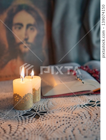 Candles lit on an altar. Image of Christ.n the background. Candles lit on an altar. Image of Christ.n the background. 139074150