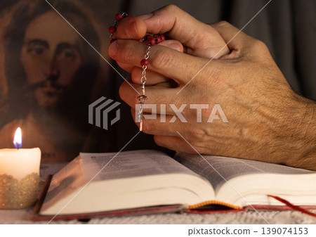 Hands of a man praying to Christ holding a rosary . Hands of a man praying to Christ holding a rosary . 139074153