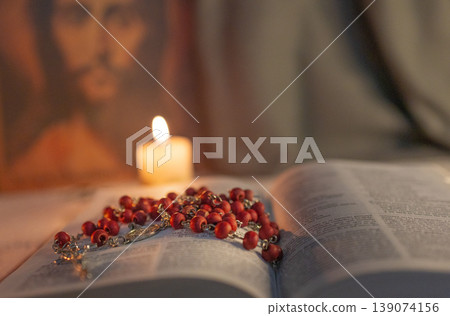 Close up photo of a rosary on The Bible .Christ face in the blurred background. 139074156