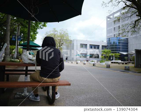 College student sitting on a bench 139074304
