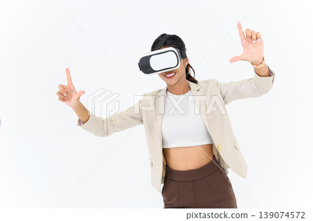 business woman in informal suit wearing VR goggles pointing in the air while standing isolated on white background. concept of Metaverse, virtual reality, future, technology, and internet of things. business woman in informal suit wearing VR goggles pointing in the air while standing isolated on white background. concept of Metaverse, virtual reality, future, technology, and internet of things. 139074572