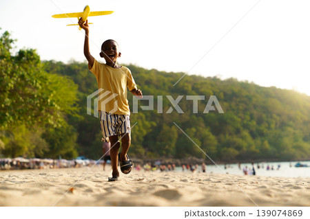 African American child playing with toy airplane on tropical beach African American child playing with toy airplane on tropical beach 139074869