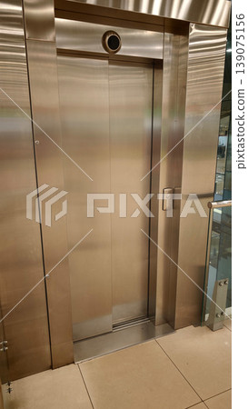 Elevator door stands closed in a modern building at a busy shopping mall in the afternoon Elevator door stands closed in a modern building at a busy shopping mall in the afternoon 139075156