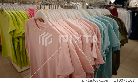 Display of colorful t-shirts in a clothing store during daytime hours 139075168