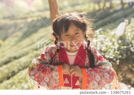 Joyful young girl in traditional ethnic clothing smiles brightly outdoors Joyful young girl in traditional ethnic clothing smiles brightly outdoors 139075261