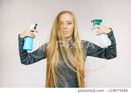 Female messy long hair holds spray bottle Female messy long hair holds spray bottle 139075696