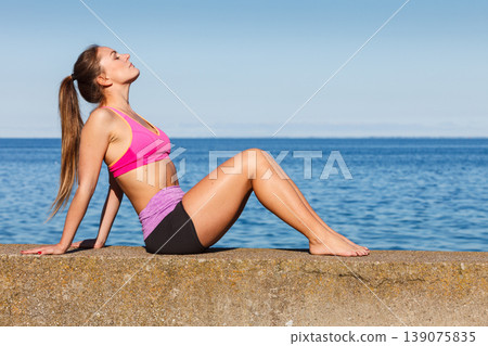 Woman doing sports exercises outdoors by seaside Woman doing sports exercises outdoors by seaside 139075835