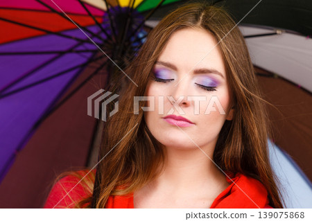 Woman standing under multicolored umbrella Woman standing under multicolored umbrella 139075868