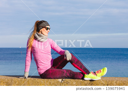 Woman resting after doing sports outdoors on cold day Woman resting after doing sports outdoors on cold day 139075941