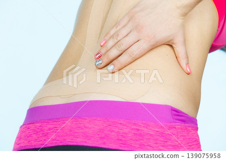Woman with medical kinesio taping on back Woman with medical kinesio taping on back 139075958