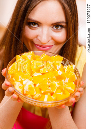 Woman holds bowl full of sliced orange fruits Woman holds bowl full of sliced orange fruits 139075977
