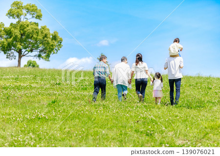 Three-generation family walking in the blue sky grassland Three-generation family walking in the blue sky grassland 139076021