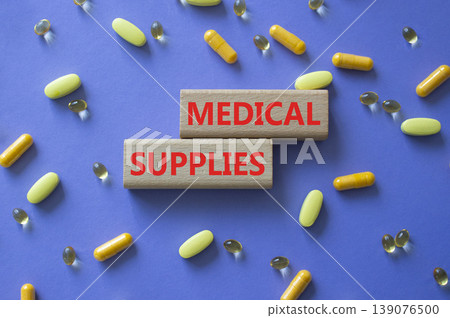 Medical supplies symbol. Concept word Medical supplies on wooden blocks. Beautiful purple background with pills. Medicine and Medical supplies. Copy space 139076500