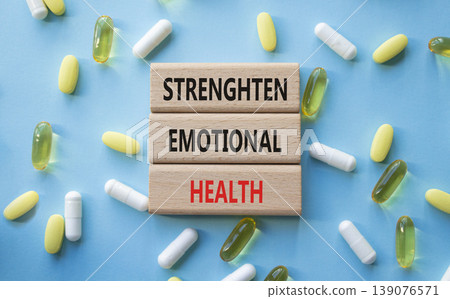 Strengthen emotional health symbol. Concept words Strengthen emotional health on wooden blocks. Beautiful blue background with pills. Healthcare and Strengthen emotional health concept. Copy space. 139076571