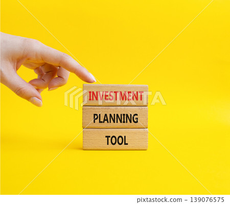 Investment planning tool symbol. Concept word Investment planning tool on wooden blocks. Businessman hand. Beautiful yellow background. Business and Investment planning tool. Copy space Investment planning tool symbol. Concept word Investment planning tool on wooden blocks. Businessman hand. Beautiful yellow background. Business and Investment planning tool. Copy space 139076575