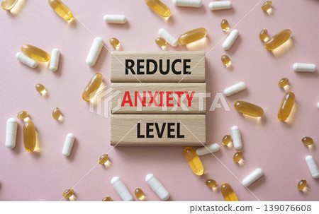 Reduce Anxiety Levels symbol. Concept words Reduce Anxiety Level on wooden blocks. Beautiful pink background with pills. Healthcare and Reduce Anxiety Levels concept. Copy space. Reduce Anxiety Levels symbol. Concept words Reduce Anxiety Level on wooden blocks. Beautiful pink background with pills. Healthcare and Reduce Anxiety Levels concept. Copy space. 139076608