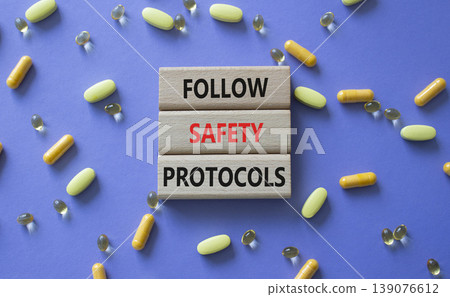 FOLLOW SAFETY PROTOCOLS symbol. Concept words PFOLLOW SAFETY PROTOCOLS on wooden blocks. Beautiful purple background with pills. Healthcare and FOLLOW SAFETY PROTOCOLS concept. Copy space. 139076612