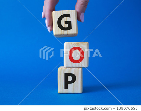 GOP - Gross Operating Profit symbol. Concept word GOP on wooden cubes. Businessman hand. Beautiful blue background. Business and GOP concept. Copy space. GOP - Gross Operating Profit symbol. Concept word GOP on wooden cubes. Businessman hand. Beautiful blue background. Business and GOP concept. Copy space. 139076653
