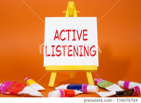 Active listening symbol. Wooden blocks with words Active listening. Beautiful orange background with paints and easel. Business and Active listening concept. Copy space. Active listening symbol. Wooden blocks with words Active listening. Beautiful orange background with paints and easel. Business and Active listening concept. Copy space. 139076784