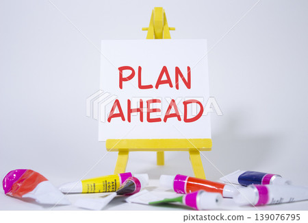 Plan ahead symbol. Wooden blocks with words Plan ahead. Beautiful white background with paints and easel. Business and Plan ahead concept. Copy space. 139076795