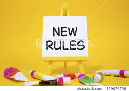 New rules symbol. Concept word Manage stress on wooden blocks. Beautiful yellow background with paints and easel. Business and New rules concept. Copy space New rules symbol. Concept word Manage stress on wooden blocks. Beautiful yellow background with paints and easel. Business and New rules concept. Copy space 139076796