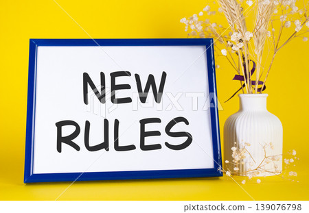 New rules symbol. Concept words New rules on beautiful wooden picture frame. Beautiful yellow background with flower vase. Business and New rules concept. Copy space. New rules symbol. Concept words New rules on beautiful wooden picture frame. Beautiful yellow background with flower vase. Business and New rules concept. Copy space. 139076798