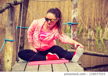 Girl training in sporty clothes on lake shore 139077035