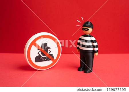 A criminal reacts to a prohibition sign against spies and fraudsters. Countering espionage strengthens security. Protection measures reduce risks from malicious activities. A criminal reacts to a prohibition sign against spies and fraudsters. Countering espionage strengthens security. Protection measures reduce risks from malicious activities. 139077395
