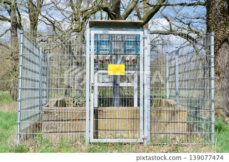 Small fenced technical utility area with a yellow sign in a park Small fenced technical utility area with a yellow sign in a park 139077474