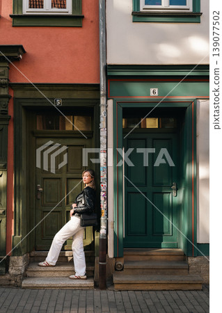 Stylish Woman Leaning by Green Door in Urban Fashion Portrait 139077502