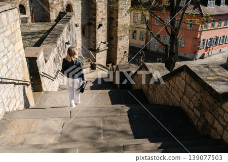 Woman Walking Down Historic Stone Stairs in European City 139077503