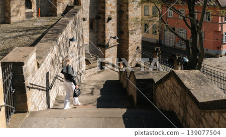 Woman Standing on Historic Stone Stairs in European Old Town 139077504
