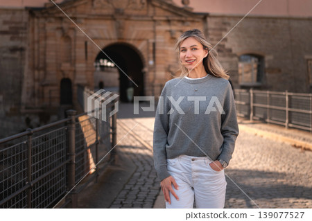 Smiling Woman Standing Near Historic Stone Gate in Europe Smiling Woman Standing Near Historic Stone Gate in Europe 139077527