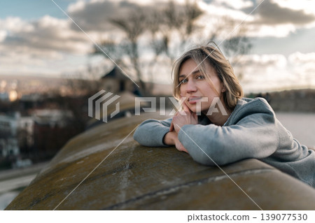 Young Woman Resting on Stone Railing in Soft Outdoor Portrait Young Woman Resting on Stone Railing in Soft Outdoor Portrait 139077530