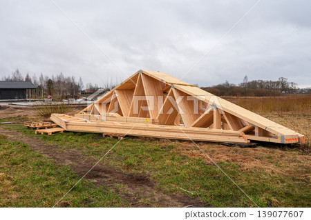 Prefabricated wooden roof trusses and timber beams prepared on rural construction site landscape 139077607