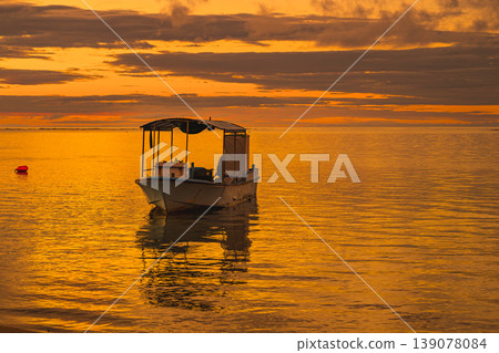 石垣島的日落景色美得令人窒息，一艘小船倒映在金色的海面上。 139078084