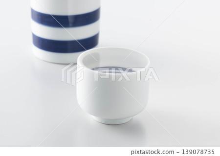 A photo of a scene where sake is poured from a sake bottle into a sake cup for tasting. 139078735