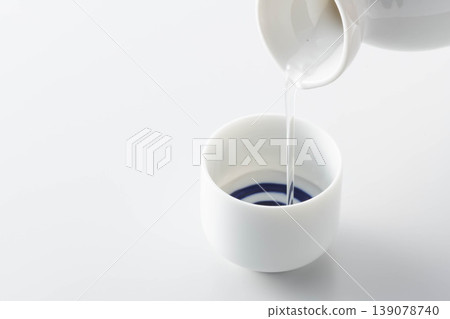一張照片展現了將清酒從酒瓶倒入酒杯中品嚐的場景。 一張照片展現了將清酒從酒瓶倒入酒杯中品嚐的場景。 139078740