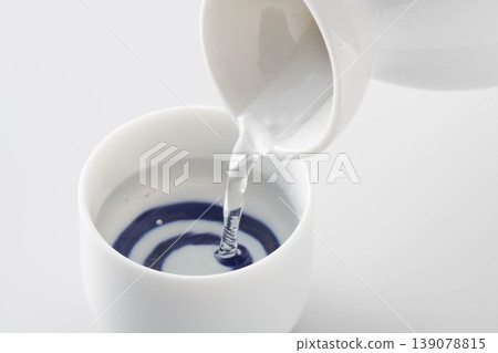 一張照片展現了將清酒從酒瓶倒入酒杯中品嚐的場景。 一張照片展現了將清酒從酒瓶倒入酒杯中品嚐的場景。 139078815