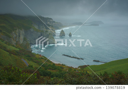 Muroran, Hokkaido, Japan - Oct 04 2024, panoramic aerial view of the picturesque Pacific ocean coast with sharp cliffs and high mountain slopes, in a storm, it's raining, at daytime, Muroran, Japan Muroran, Hokkaido, Japan - Oct 04 2024, panoramic aerial view of the picturesque Pacific ocean coast with sharp cliffs and high mountain slopes, in a storm, it's raining, at daytime, Muroran, Japan 139078819
