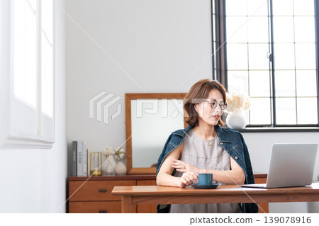 一位中年婦女在客廳使用電腦。 139078916