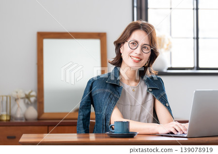 在客廳裡使用電腦的中年女人 在客廳裡使用電腦的中年女人 139078919